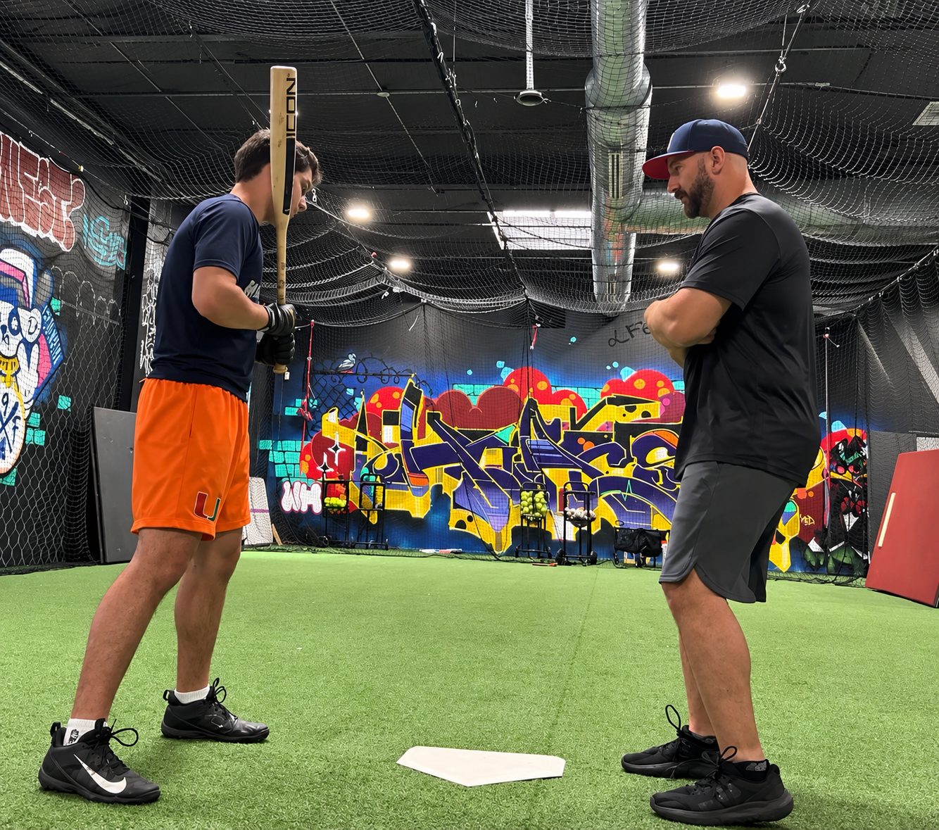 Coach Steve working with Joseph on his batting stance during a one-on-one hitting lesson in an indoor batting cage. coach steve with joseph.jpg