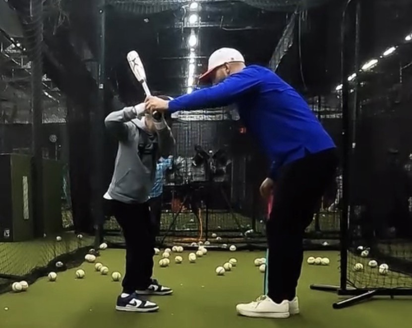 Coach Steve guiding a hitter's bat path in the cage while training game-speed decisions